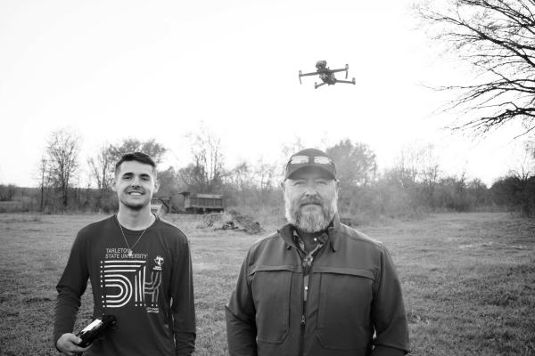 Logan Rice (left) and his dad Lawrance Rice with their drone hovering in the background, about to scout a distant field for wild hogs. Photo by Luke Clayton
